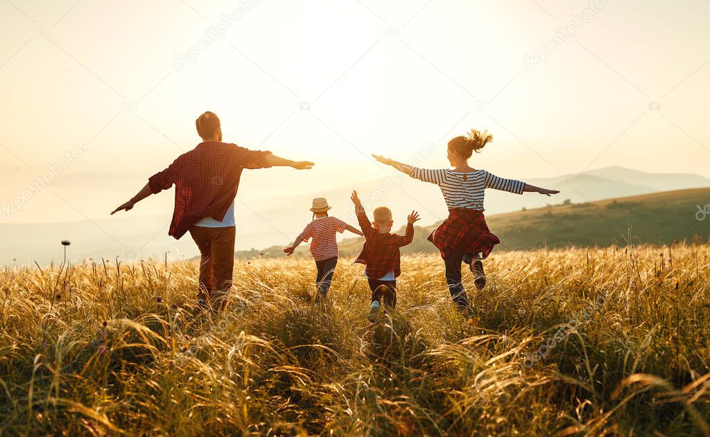 Happy family: mother, father, children son and daughter on sunse