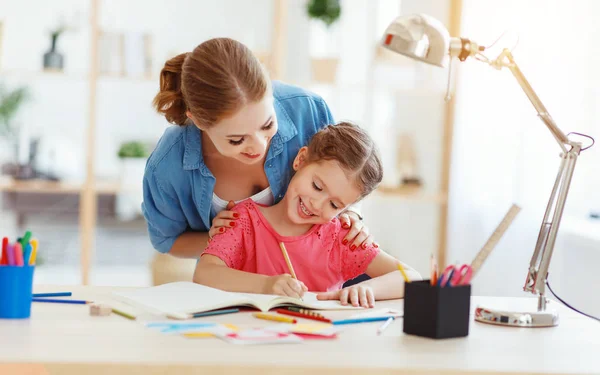 Мать и ребенок дочь делает домашнее задание писать и читать в — стоковое фото