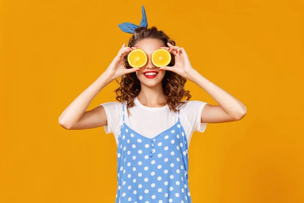 Alegre joven rizado chica con naranja en amarillo bac —  Fotos de Stock