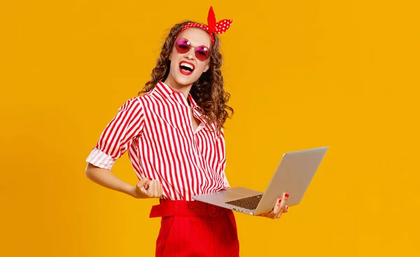 Grappige vrolijke vrouw met laptop op gele backgroun — Stockfoto