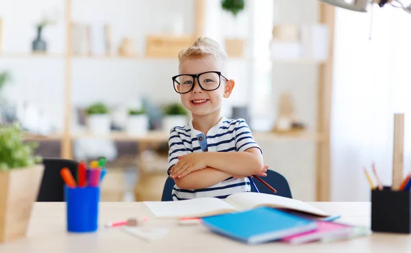 Niño divertido haciendo tareas de escritura y lectura en hom —  Fotos de Stock