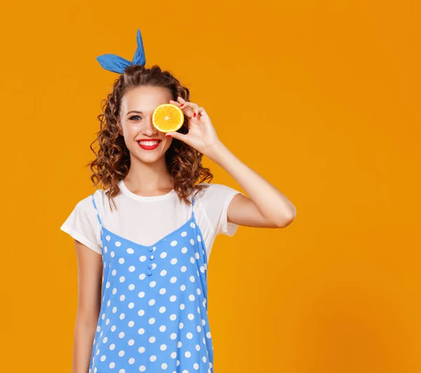 Joyeuse jeune femme bouclée fille avec orange sur bac jaune — Photo