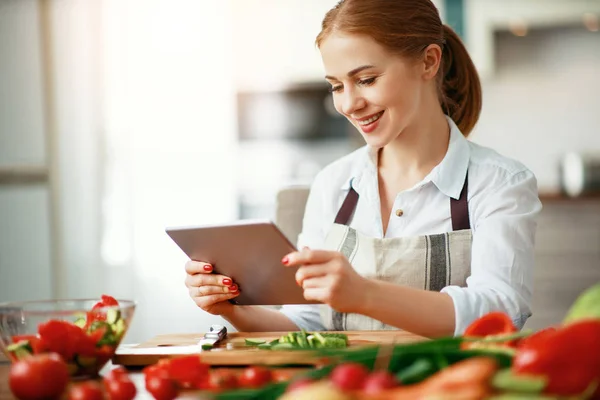Gelukkige vrouw bereidt groenten in de keuken op recept met — Stockfoto