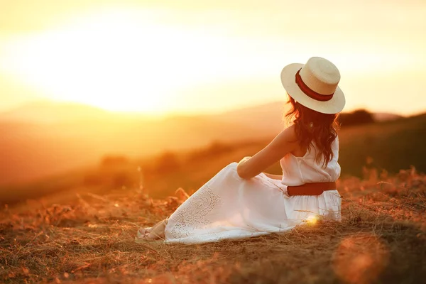 Mulher feliz de pé com as costas no pôr do sol na natureza — Fotografia de Stock