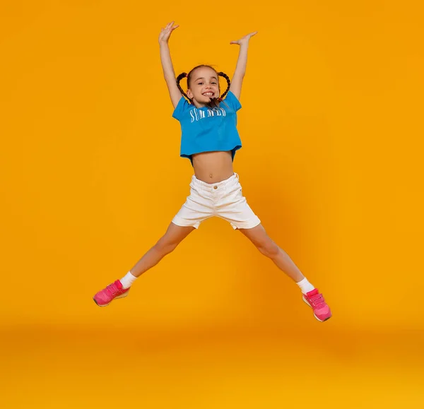 Grappige kind meisje springen op gekleurde gele pagina — Stockfoto