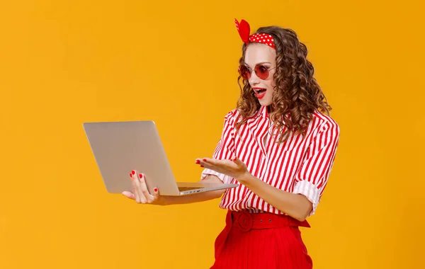 Grappige vrolijke vrouw met laptop op gele backgroun — Stockfoto