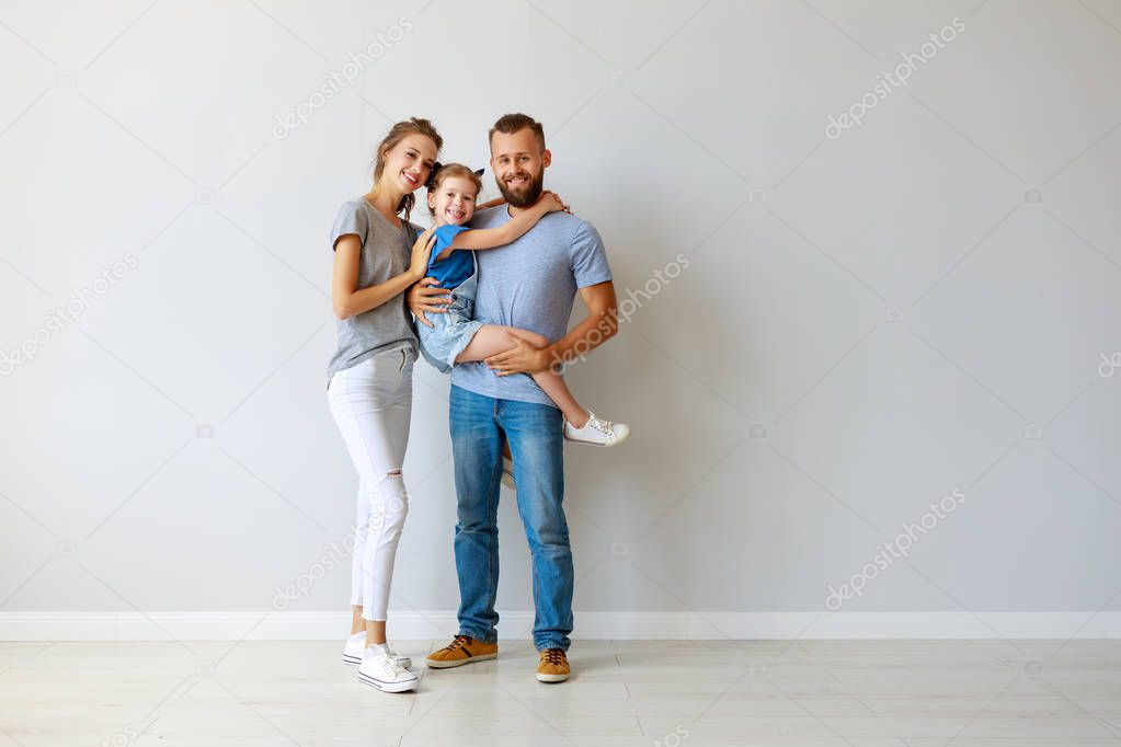 happy family mother father and child  near an empty wall