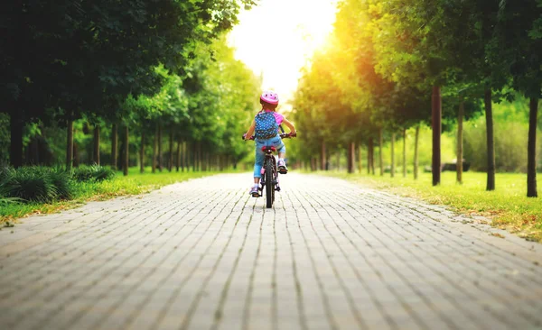 Happy cheerful child girl riding a bike in Park in natur — Stock Photo, Image