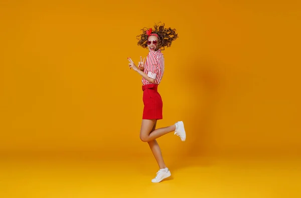 Concepto feliz emocional joven mujer en rojo saltar sobre amarillo —  Fotos de Stock