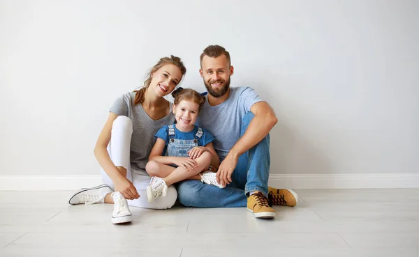 Feliz familia madre padre e hijo cerca de una pared vacía — Foto de Stock