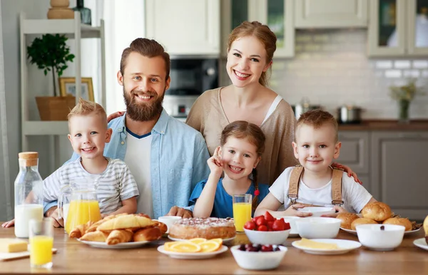 Família mãe pai e filhos têm café da manhã na cozinha em m — Fotografia de Stock