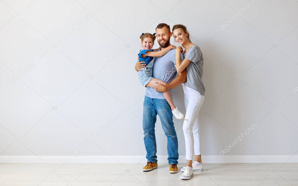 happy family mother father and child  near an empty wall