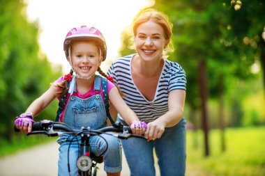 mutlu aile anne çocuk kızı bir bisiklete binmek öğretir