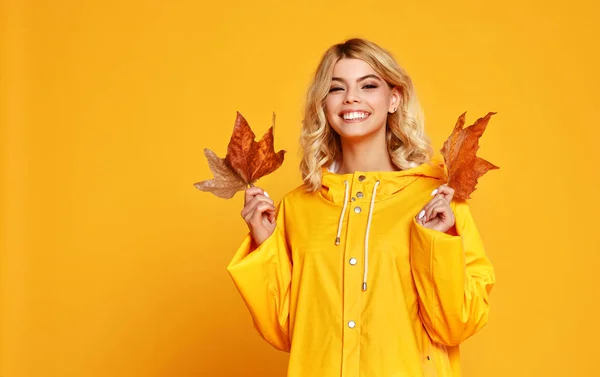 色付きの黄色のバックグルに秋の葉を持つ幸せな感情的な女の子 — ストック写真