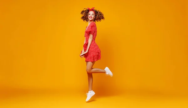 Concepto feliz emocional joven mujer en rojo saltar sobre amarillo —  Fotos de Stock