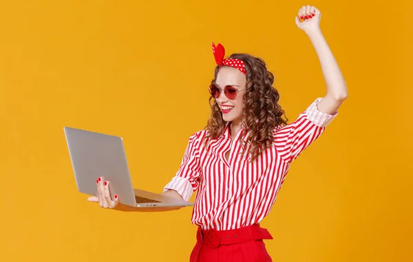 Grappige vrolijke vrouw met laptop op gele backgroun — Stockfoto