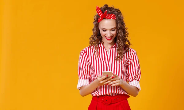 Rolig glad kvinna med telefon på gul bakgrunds — Stockfoto