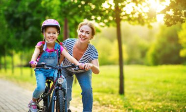 mutlu aile anne çocuk kızı bir bisiklete binmek öğretir