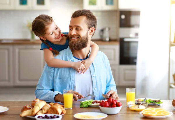 Счастливый отец семьи с ребенком кормит свою дочь на кухне — стоковое фото