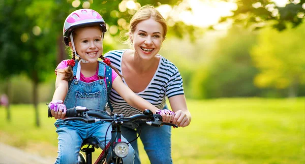 幸せな家族の母は子供の娘に自転車に乗るように教えます — ストック写真