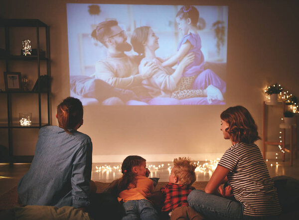 family mother father and children watching projector, TV, movies