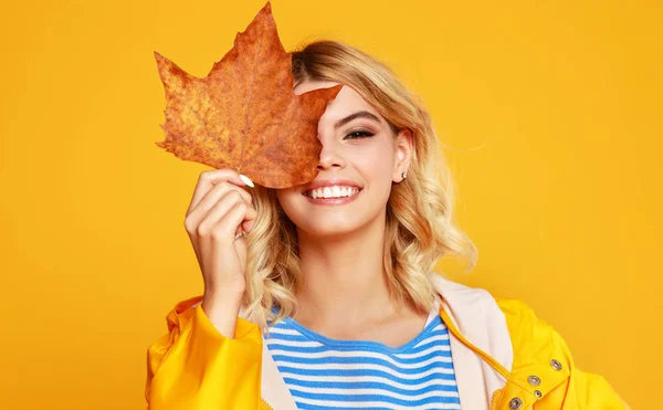 Happy emotional girl with autumn leaves on colored yellow backgr — Stock Photo, Image