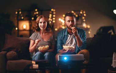  Aile çift kanepede evde televizyon projektörü izlerken