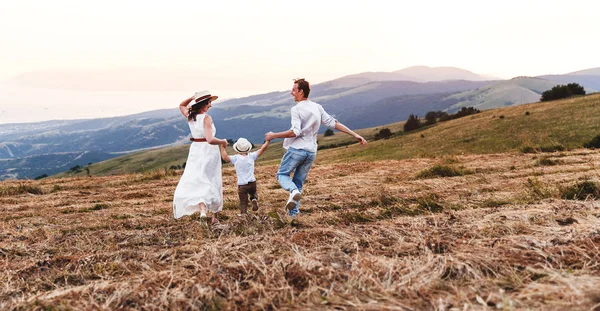 Pai de família feliz de mãe e filho de criança na natureza no pôr do sol — Fotografia de Stock