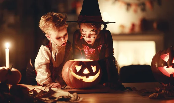 Счастливые дети в костюмах ведьмы и вампира в темном доме — стоковое фото