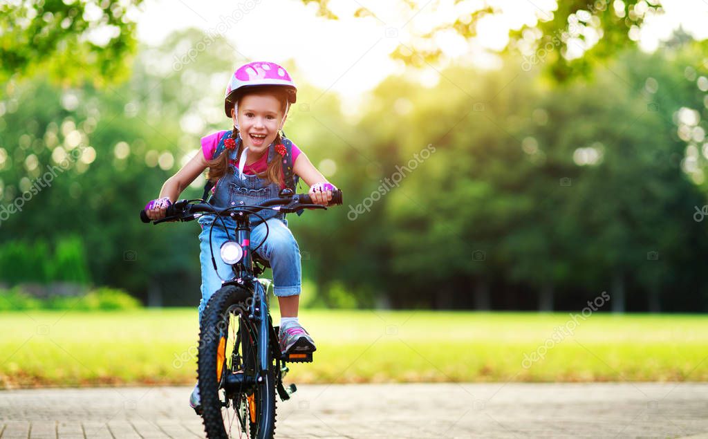 happy cheerful child girl riding a bike in Park in natur