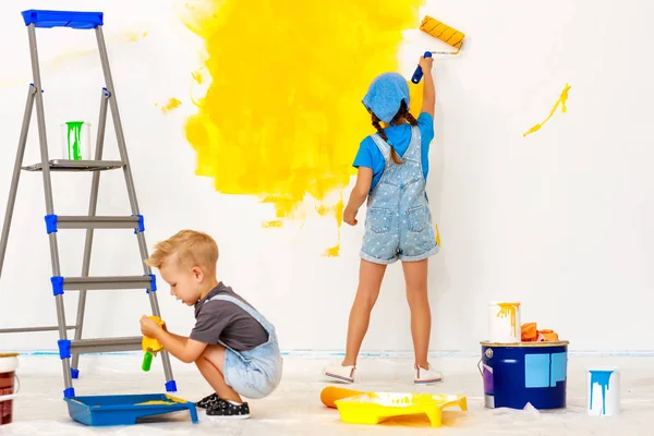 Repair in apartment. Happy children boy and girl paints wall — Stock Photo, Image