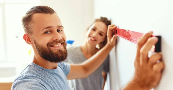 Jovem casal feliz está reparando e pintura parede em hom — Fotografia de Stock