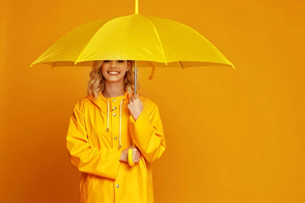 Glückliche emotionale Mädchen lachen mit Regenschirm auf farbigem Gelb — Stockfoto