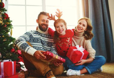 Mutlu aile Noel ağacının yakınındaki evde hediyelerle