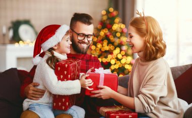 Mutlu aile Noel ağacının yakınındaki evde hediyelerle