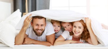 Mutlu aile anne, baba ve çocuklar gülüyor, oynuyor ve...