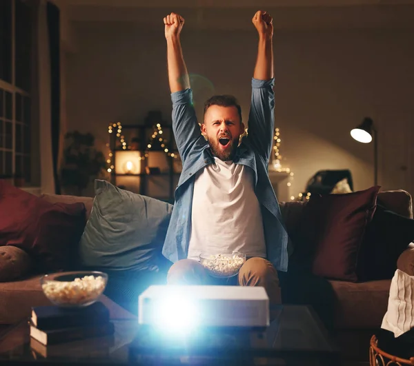 Jovem líder de torcida masculino assistindo futebol na tv projetor em casa — Fotografia de Stock