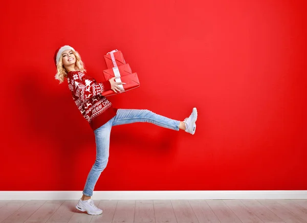 Happy young cheerful girl laughs and jumps in christmas hat and — Stock Photo, Image