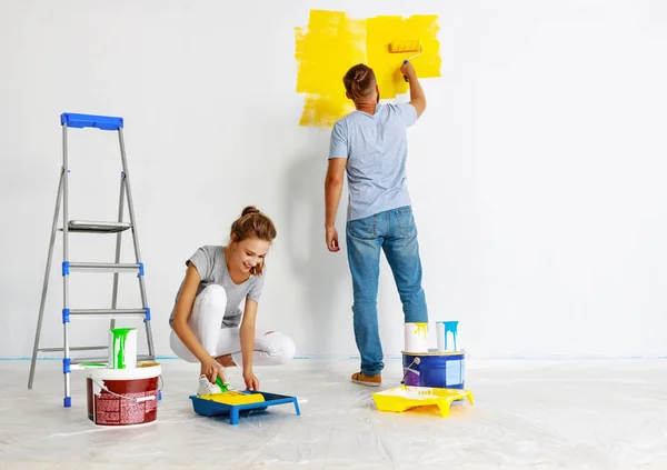 Young happy couple is repairing and painting   wall at hom — Stock Photo, Image