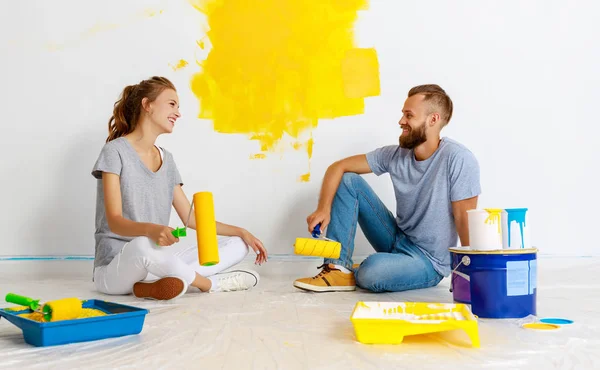 Ung glad par reparerar och målning vägg vid hom — Stockfoto