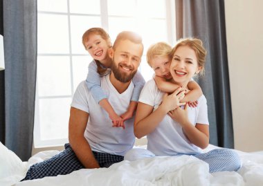 Mutlu aile anne, baba ve çocuklar gülüyor, oynuyor ve...