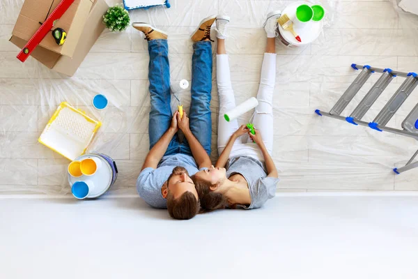 Jovem casal cansado está reparando e pintura parede em hom — Fotografia de Stock