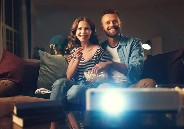 Семейная пара смотрит телевизионный проектор дома на софе — стоковое фото
