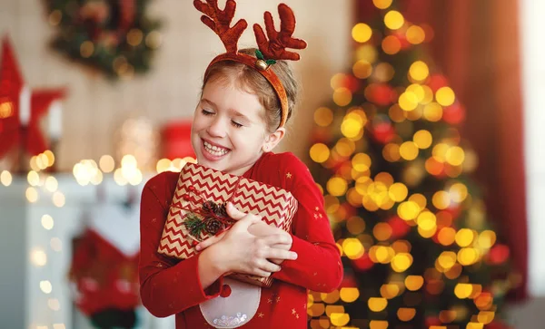 Gelukkig lachen kind meisje met kerstcadeau op hom — Stockfoto