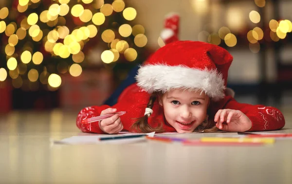 Dziecko dziewczynka pisanie listu santa domu w pobliżu tre Boże Narodzenie — Zdjęcie stockowe