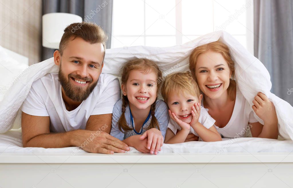 happy family mother, father and children laughing, playing and s