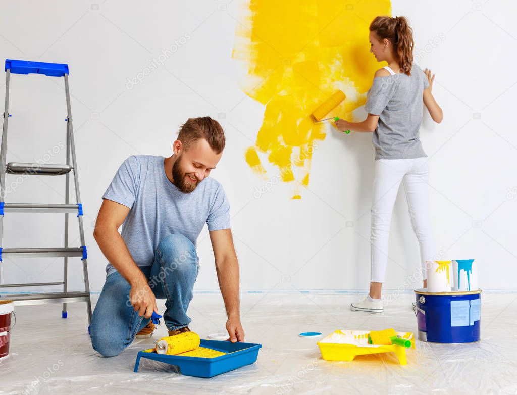 young happy couple is repairing and painting   wall at hom