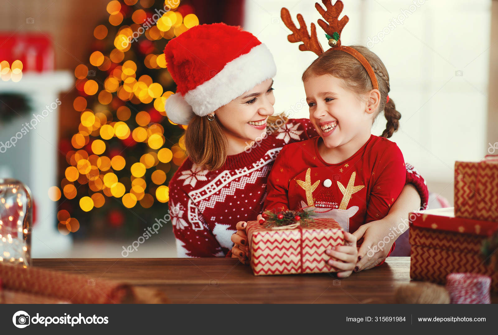 Happy family mother and child pack Christmas gifts at home near