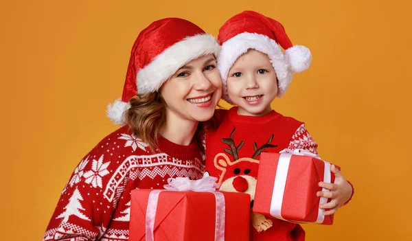 Ευτυχισμένη οικογένεια μητέρα και παιδί γιος με χριστουγεννιάτικα δώρα στο κίτρινο — Φωτογραφία Αρχείου