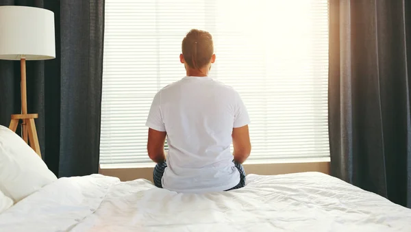 Young man sitting back woke up in his bed in   morning by window — Stock Photo, Image